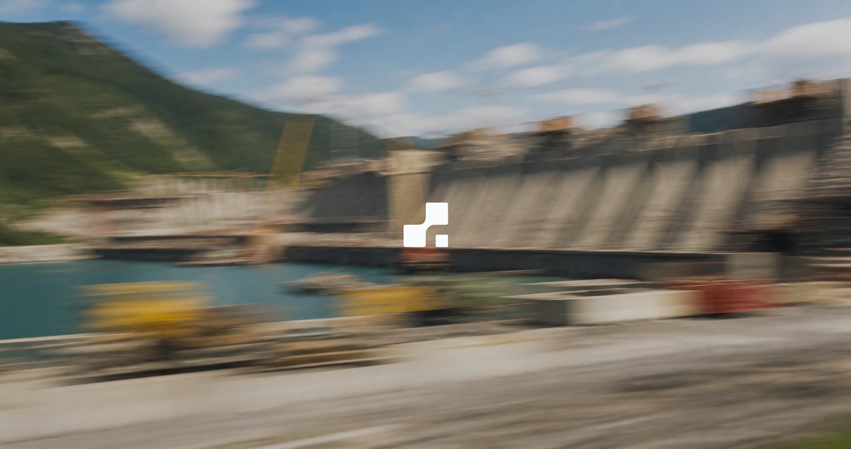 Motion-blurred summer view of a concrete dam under construction in green mountains, overlaid with the Aplon mark