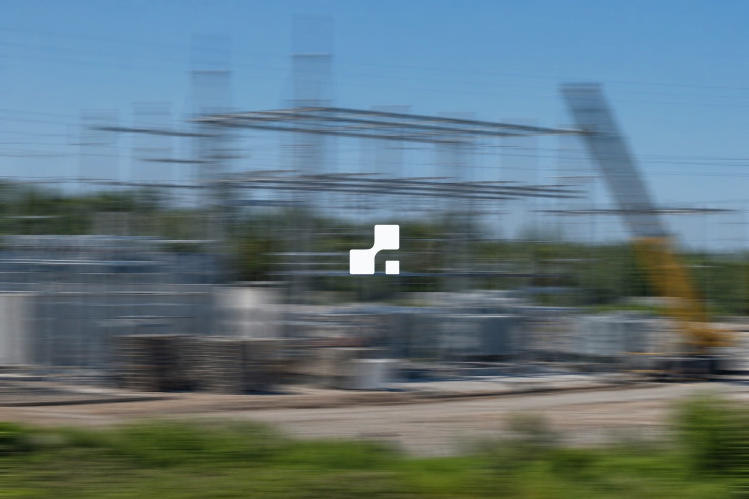 Fully motion-blurred summer view of an electrical substation under construction with steel structures, a crane, and green vegetation, overlaid with the Aplon mark